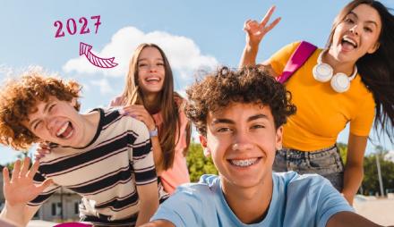 4 junge Menschen in bunter Kleidung lachen in die Kamera