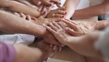 Beschnittene Aufnahme einer Gruppe von Menschen, die sich die Hände reichen