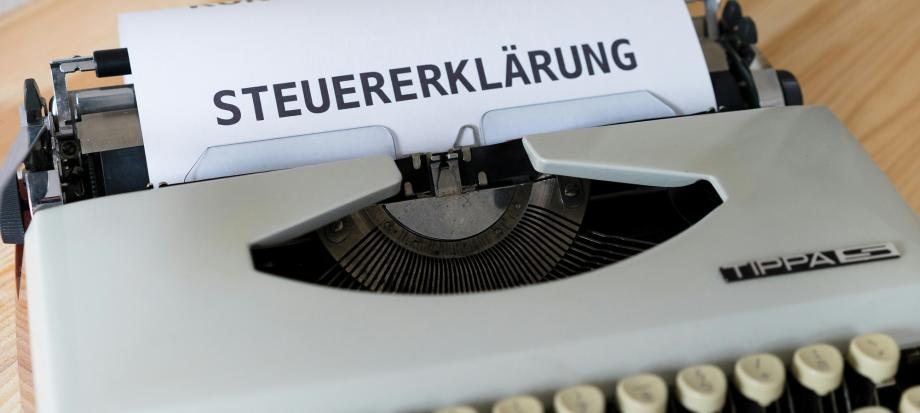 Schreibmaschine mit weißem Blatt, auf dem "Steuererklärung" steht