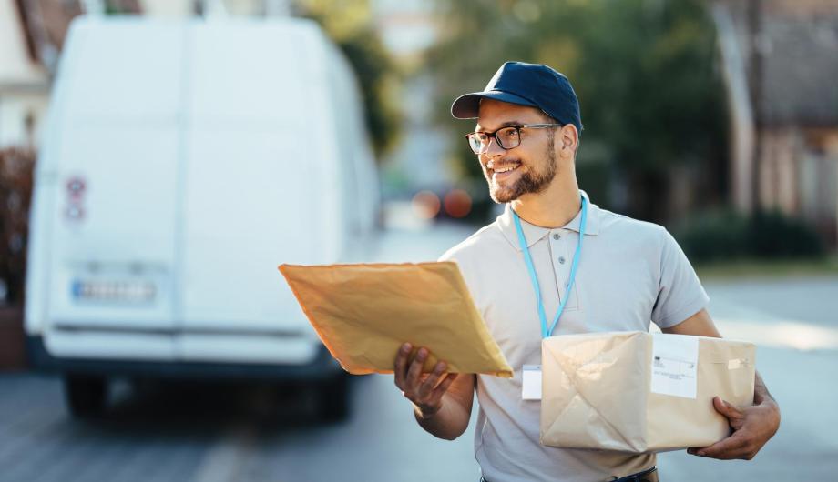 Lächelnder Postbote mit Paketen in der Hand