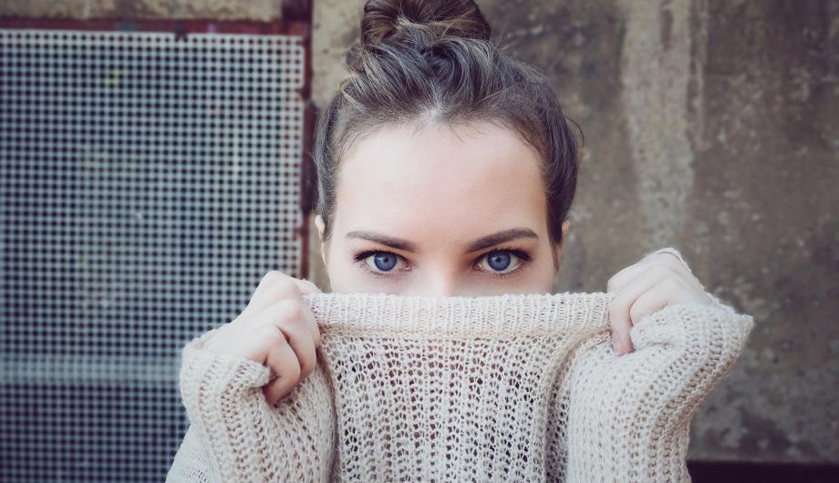 Frau, die sich ihren Pullover halb über das Gesicht zieht