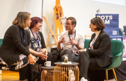 4 Personen auf grünen Sofas reden miteinander