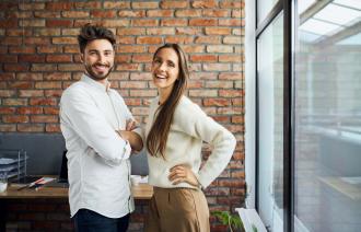 Frau und Mann im Büro lächeln in die Kamera