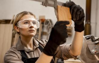 Tischlerin mit Brille mit Werkzeug zum Messen von Holz