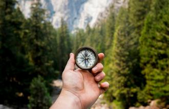 Hand mit Kompass inmitten der Natur