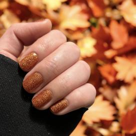 Hand mit orangenen glitzernen Nägeln