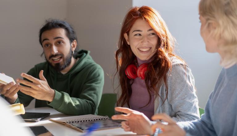 3 Personen sitzen an einem Tisch und diskutieren