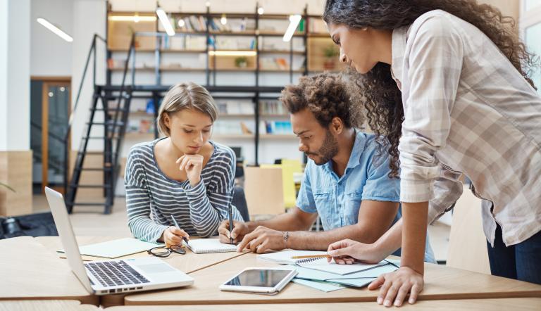 Gruppe von drei jungen multiethnischen Geschäftsleuten im Co-Working-Space