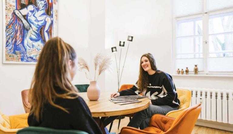 2 Frauen an einem Tisch, die miteinander sprechen