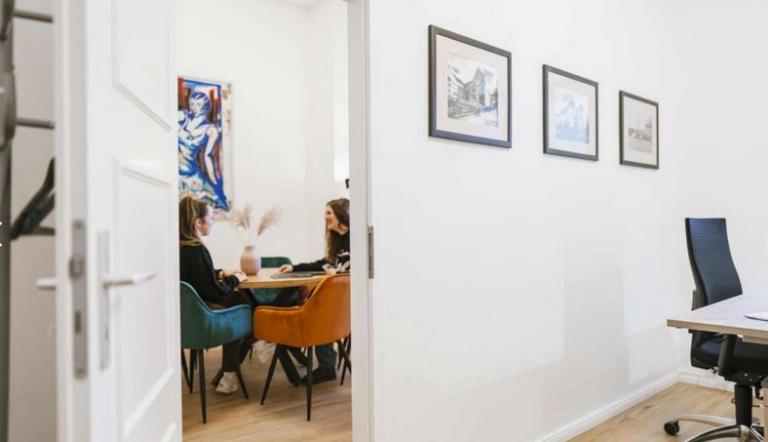 2 Frauen an einem Tisch, die miteinander sprechen im Büro