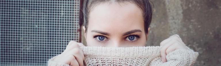 Frau, die sich ihren Pullover halb über das Gesicht zieht