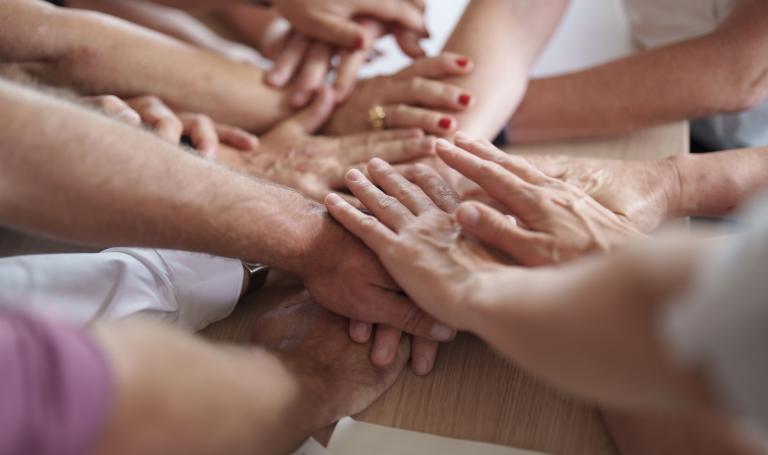 Beschnittene Aufnahme einer Gruppe von Menschen, die sich die Hände reichen