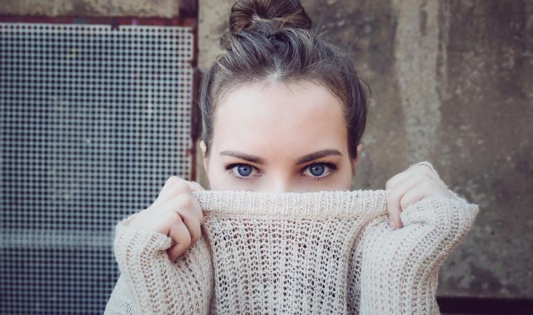 Frau, die sich ihren Pullover halb über das Gesicht zieht